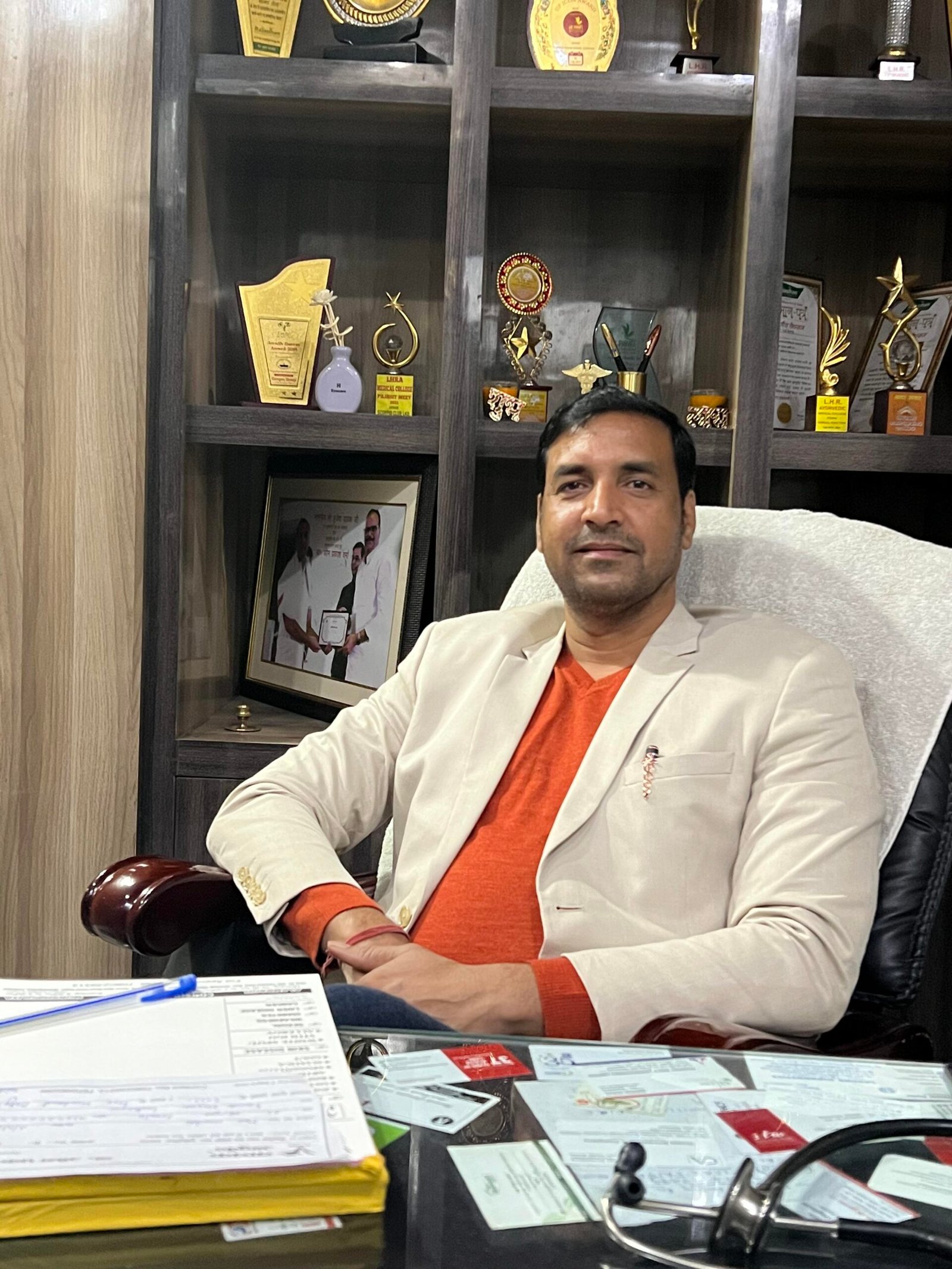 A man in an office chair with papers and a laptop, working diligently in a professional setting.