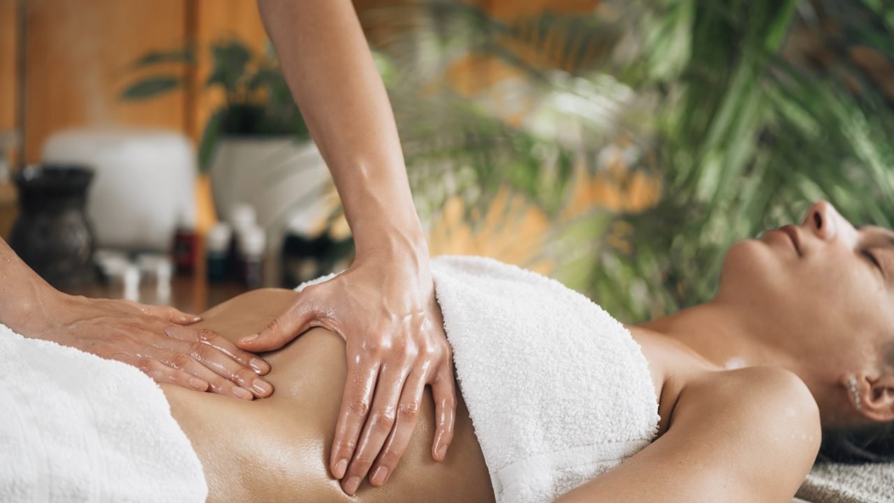 Woman receiving ayurvedic stomach massage in spa.