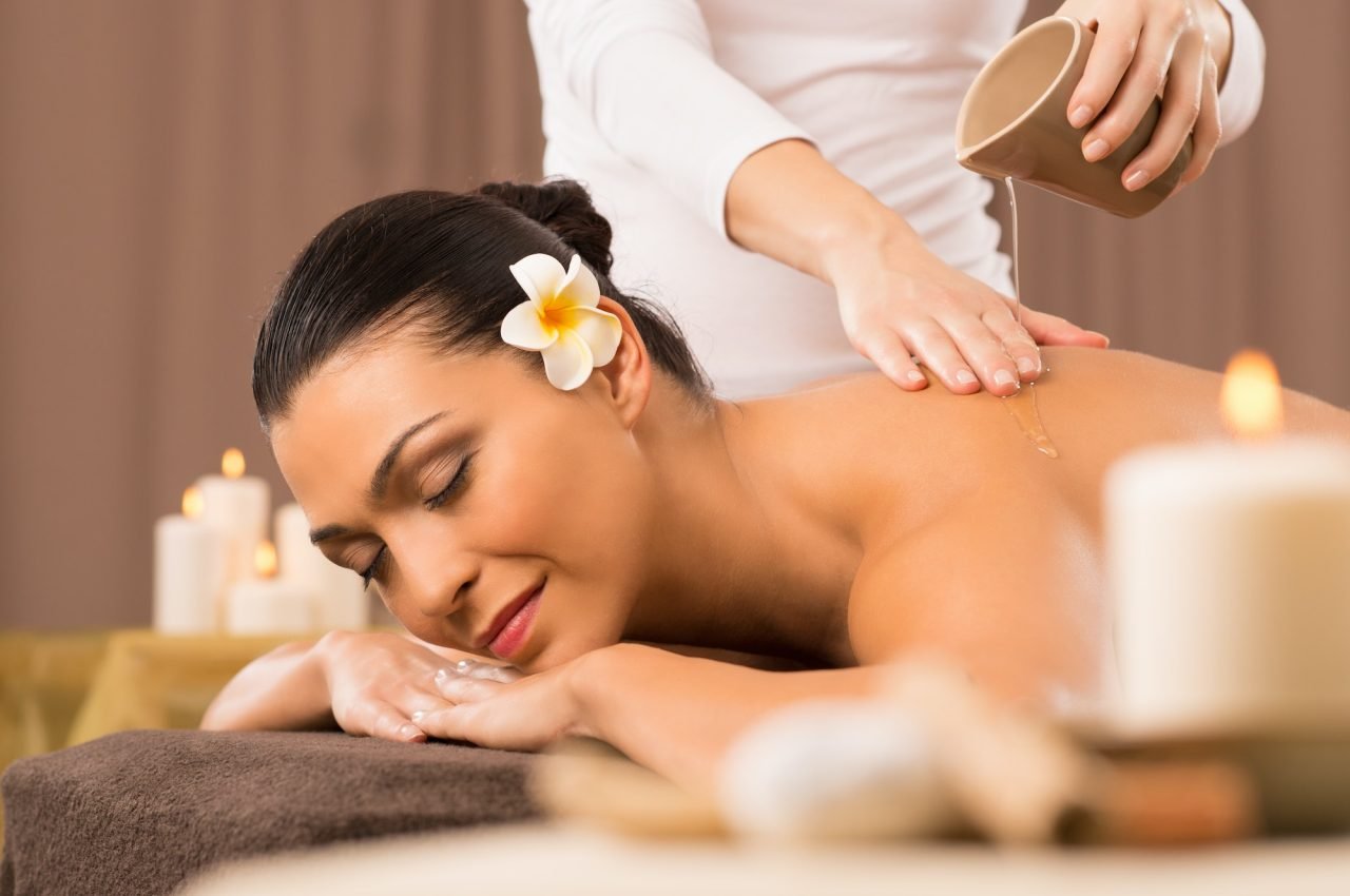 A woman receiving a back oil massage at a spa, enjoying a relaxing